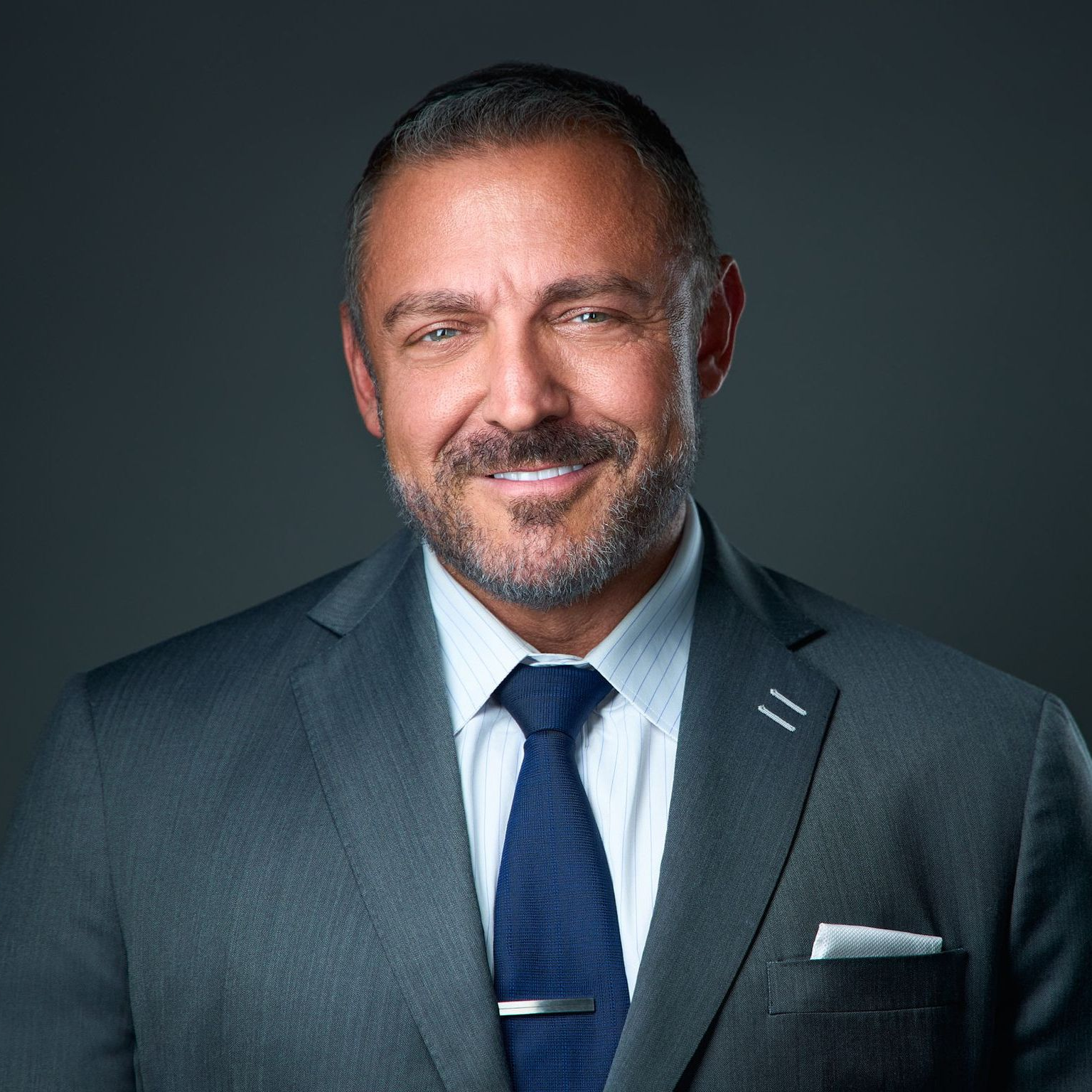 A man in a suit and tie is smiling for the camera.