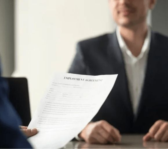 A man is holding a piece of paper that says employment agreement