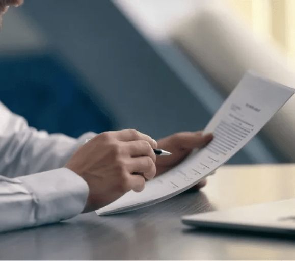 A man is writing on a piece of paper with a pen