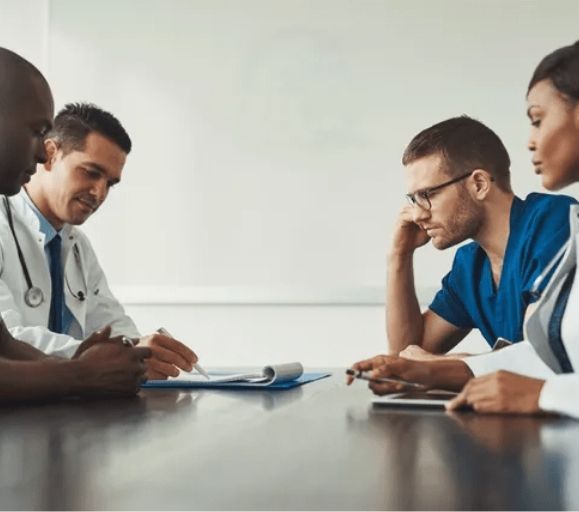 A group of doctors are sitting around a table having a meeting.