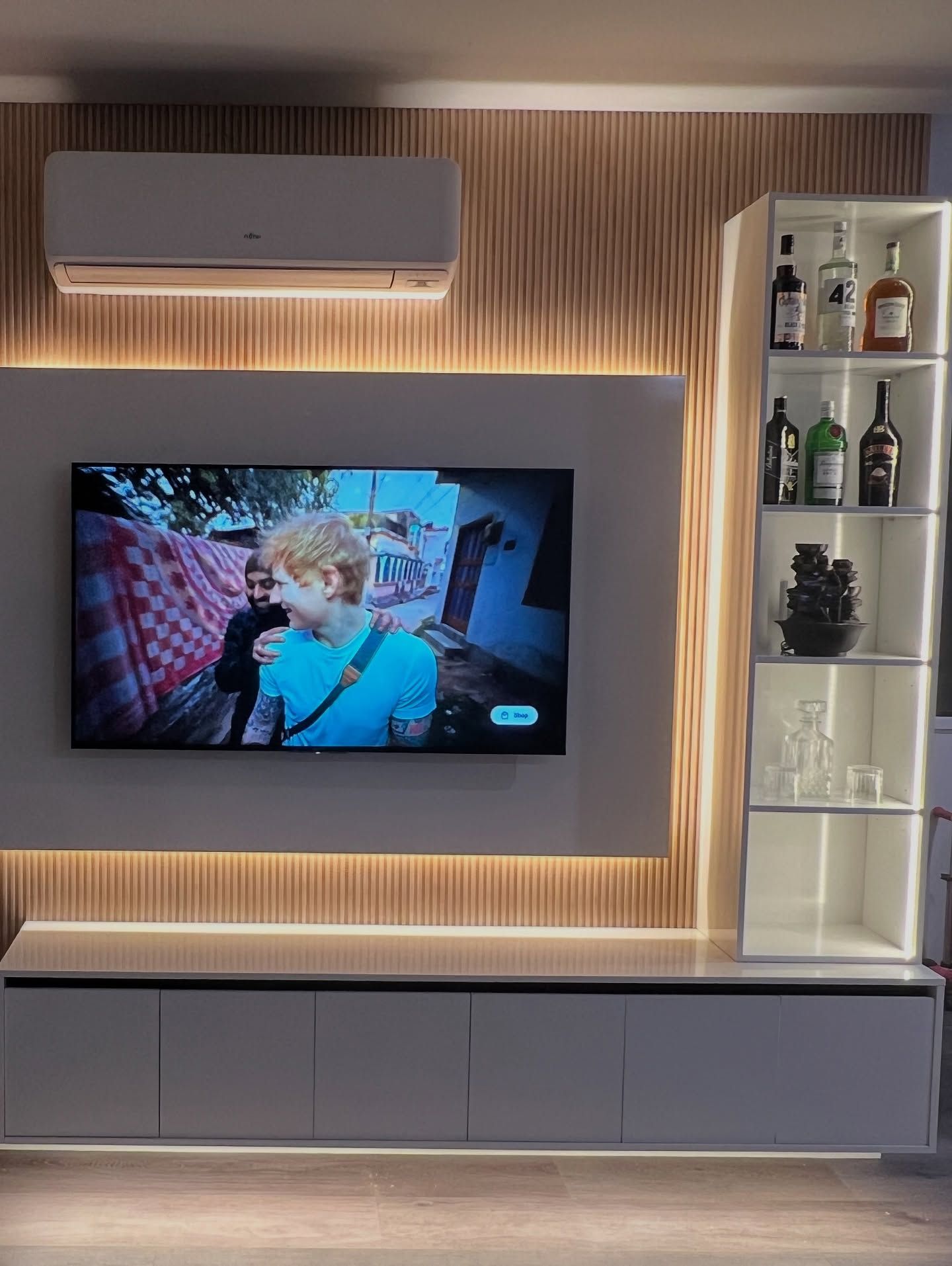 Living room entertainment center with TV, storage, and liquor cabinet; illuminated with LED lights.