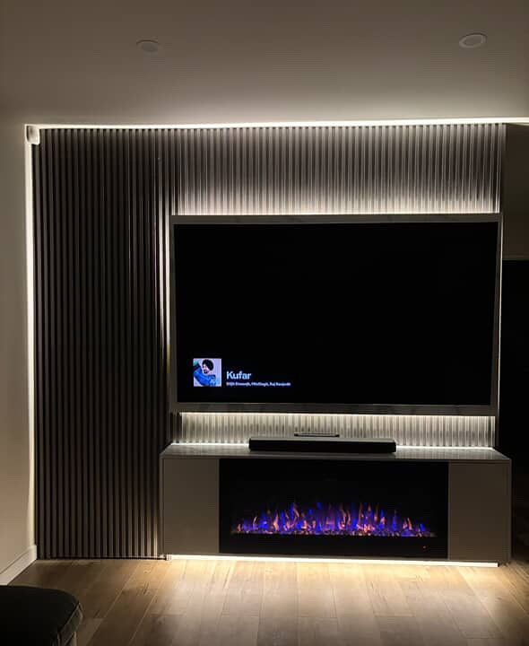 Modern media wall with large TV, LED strip lighting, and electric fireplace.