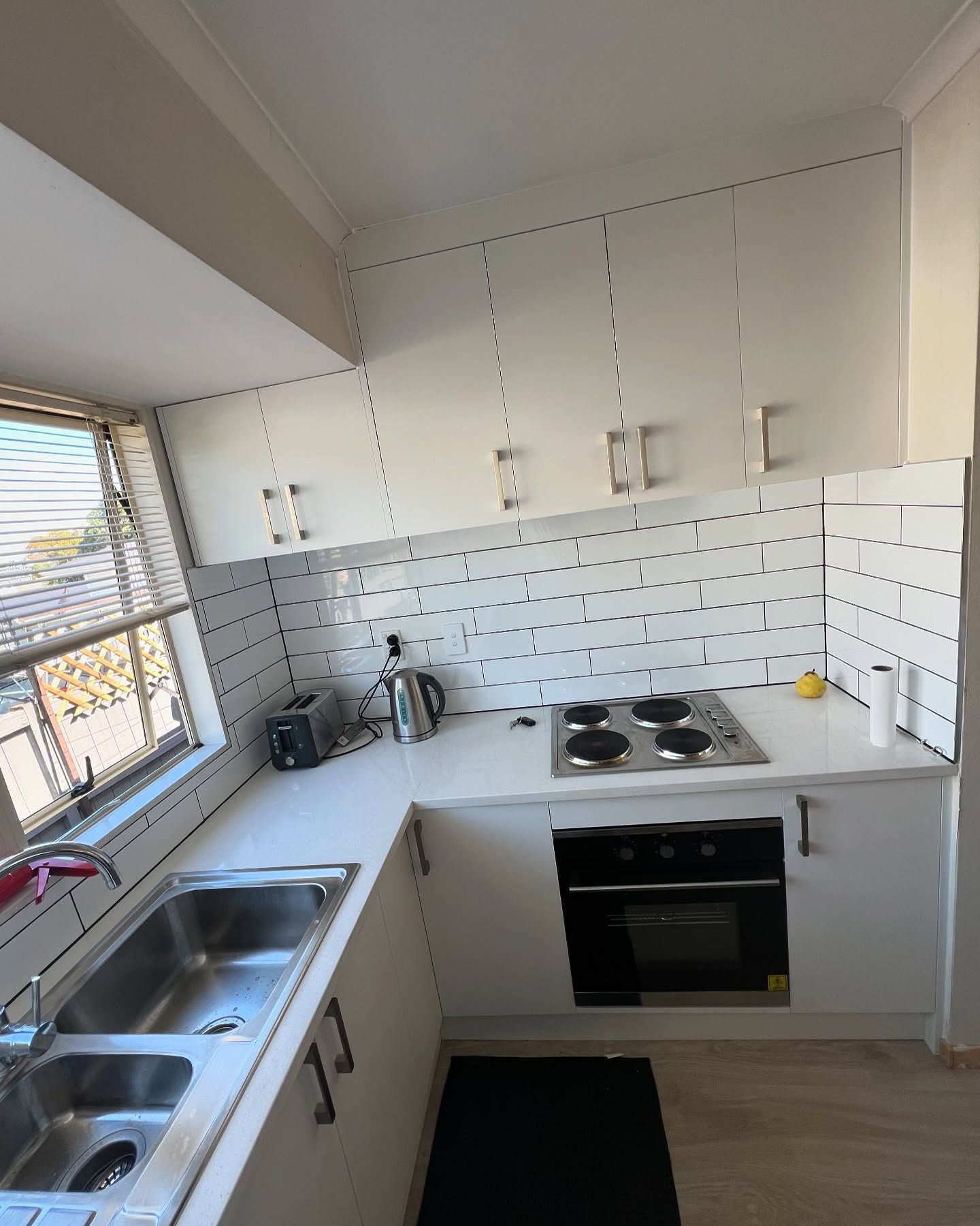 White kitchen with stainless steel appliances and white countertops.