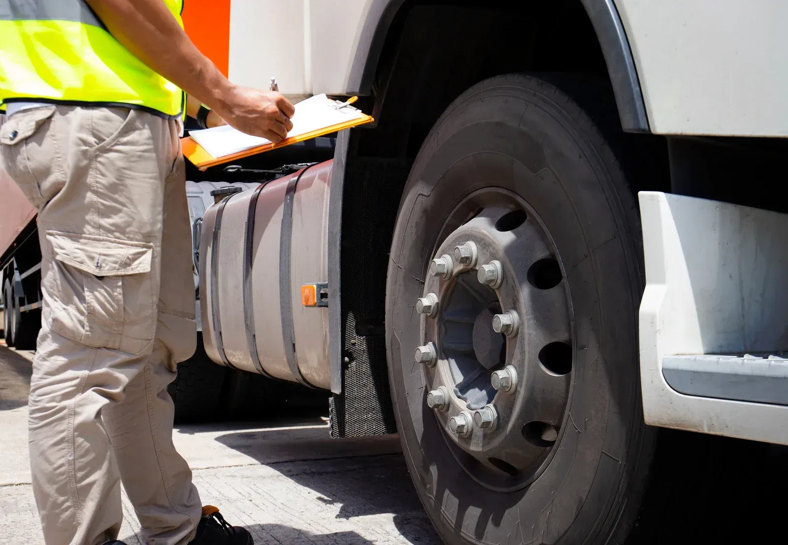 A man is writing on a clipboard next to a truck
