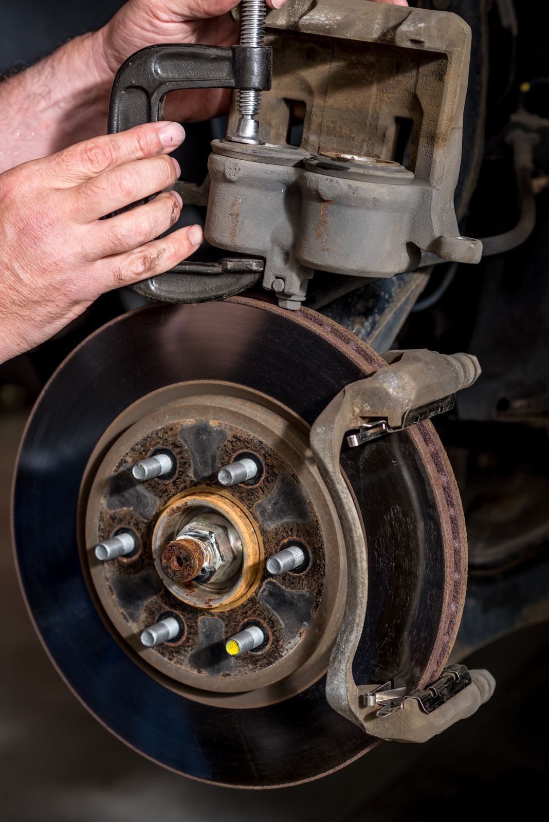 A man is fixing a brake caliper on a car.