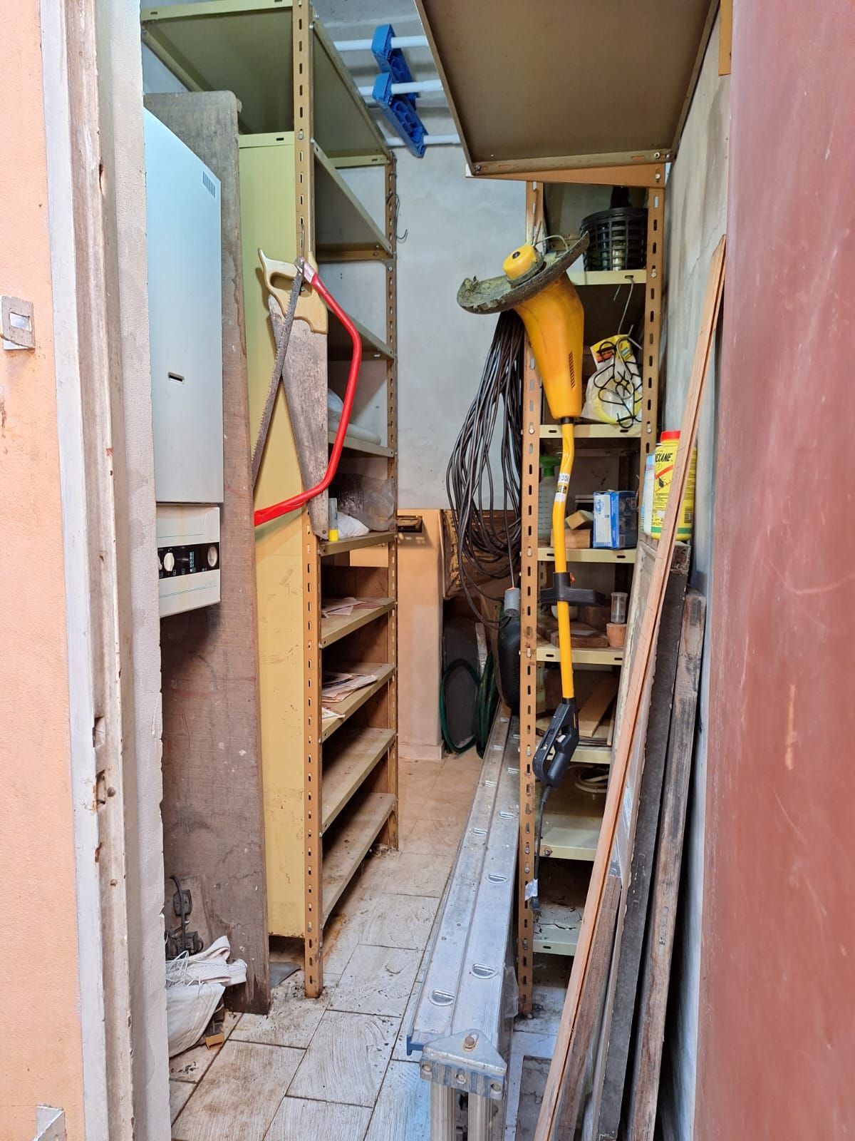 Espacio de almacenamiento estrecho con estantes para herramientas y suministros.