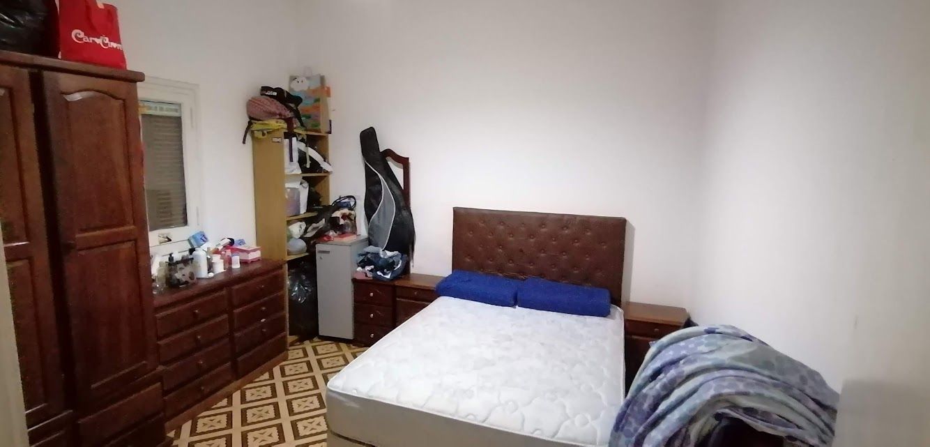 Un dormitorio desordenado con una cama, una cómoda y un armario.