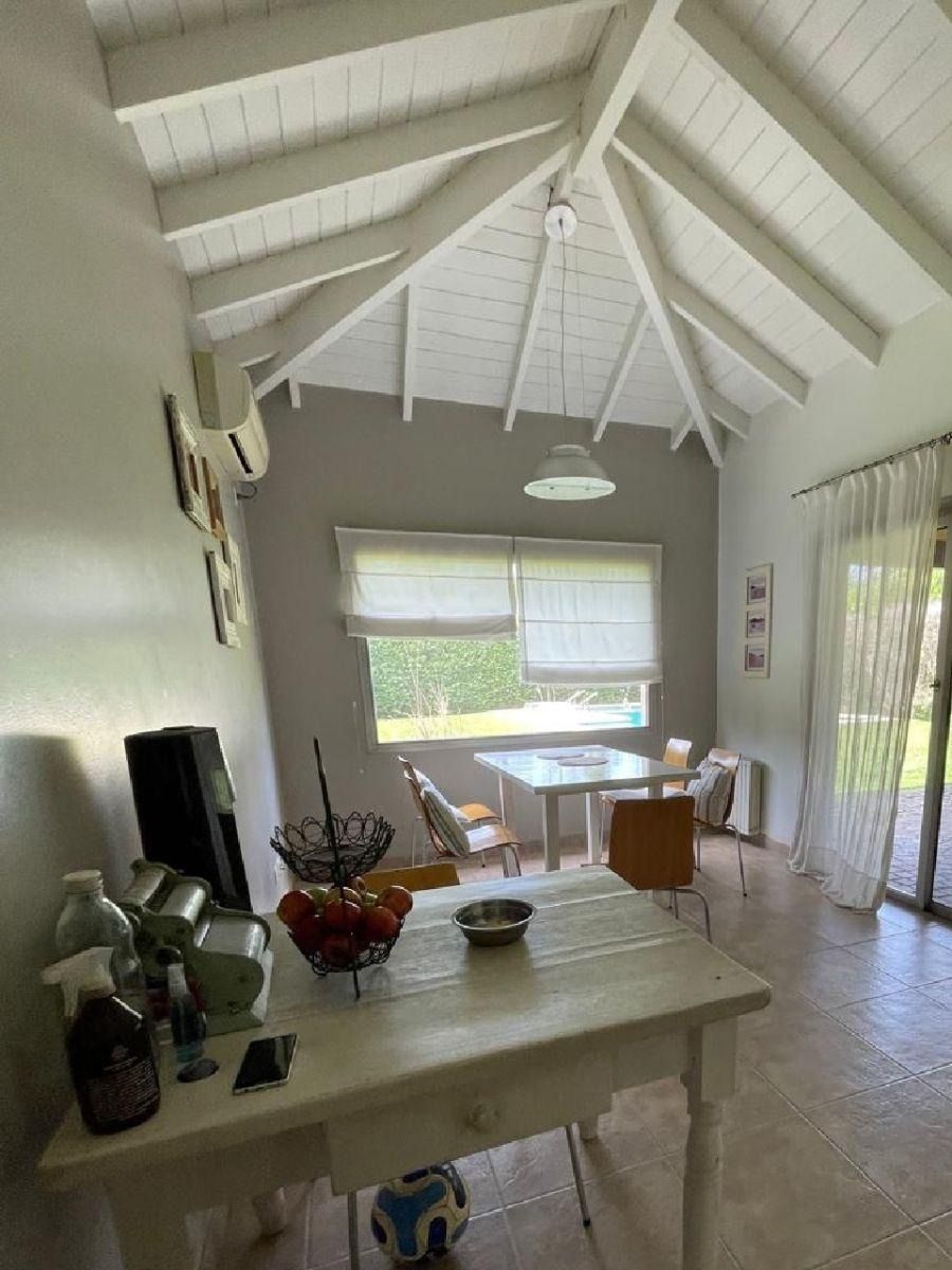 Cocina luminosa con techo de madera blanca, mesa de comedor y gran ventanal.