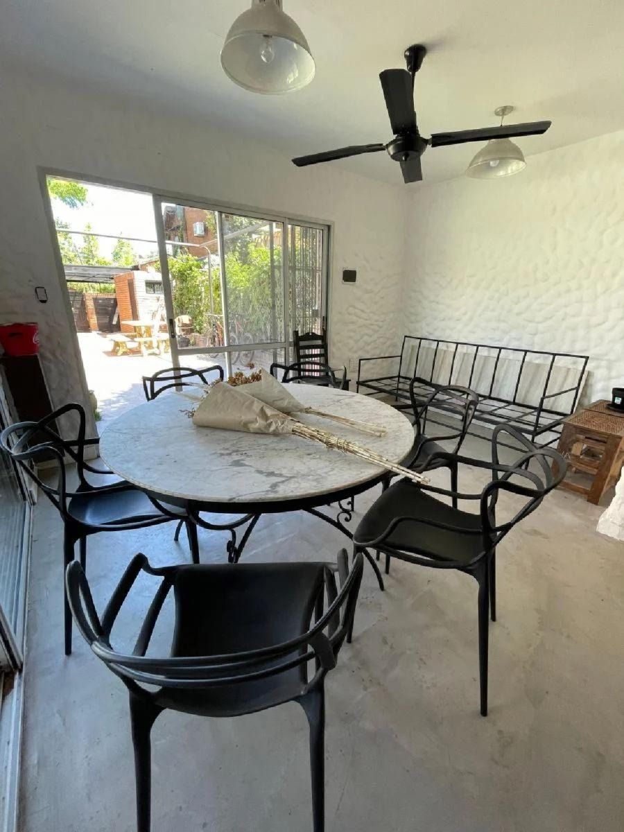 Un comedor con una mesa, sillas negras y un sofá de metal cerca de una puerta corrediza de vidrio.