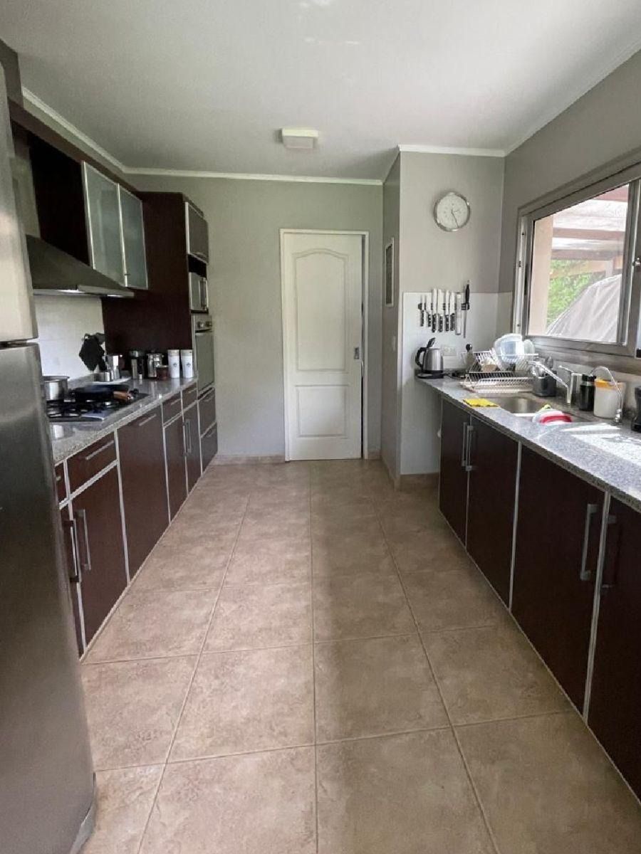 Cocina con armarios marrones, paredes grises y una puerta blanca al fondo.