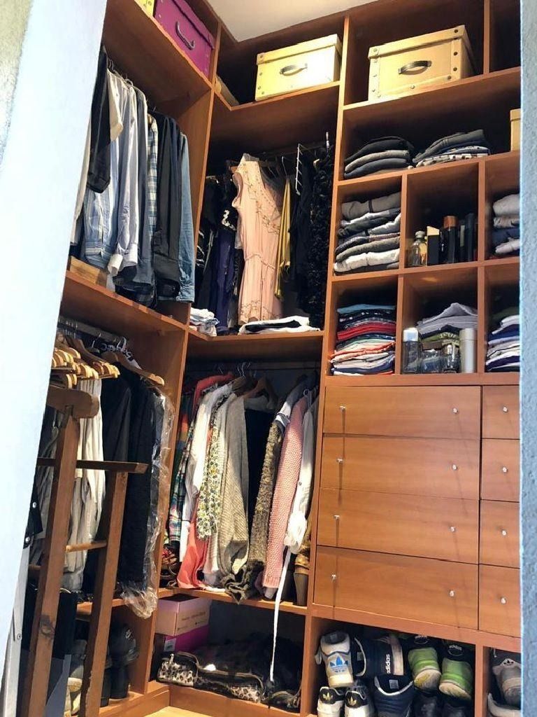Vestidor de madera con ropa colgada en perchas y estantes, cajas y ropa doblada.