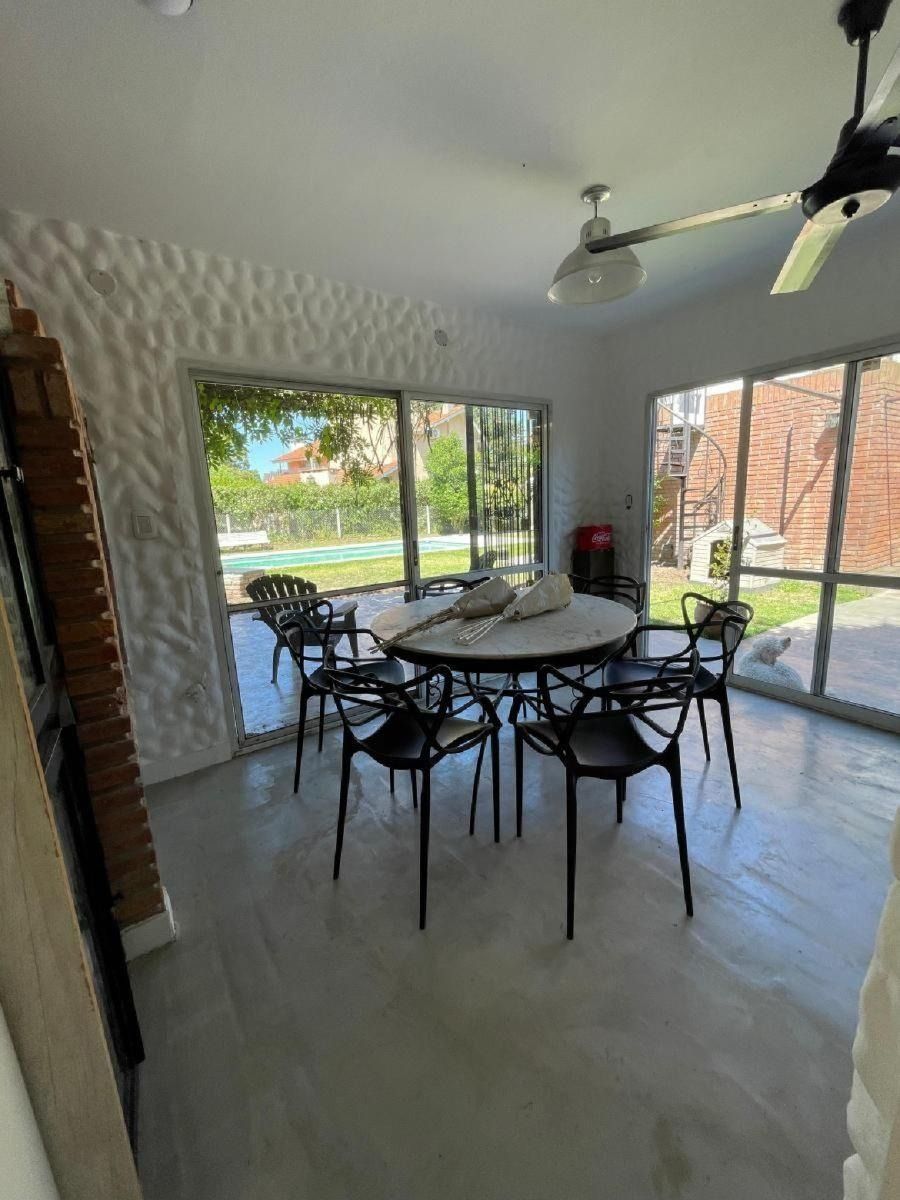 Comedor con mesa redonda y sillas negras, junto a una ventana con vistas al patio trasero.