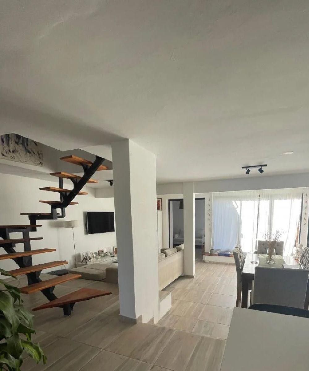 Interior de una casa moderna con escalera, sala de estar y comedor.