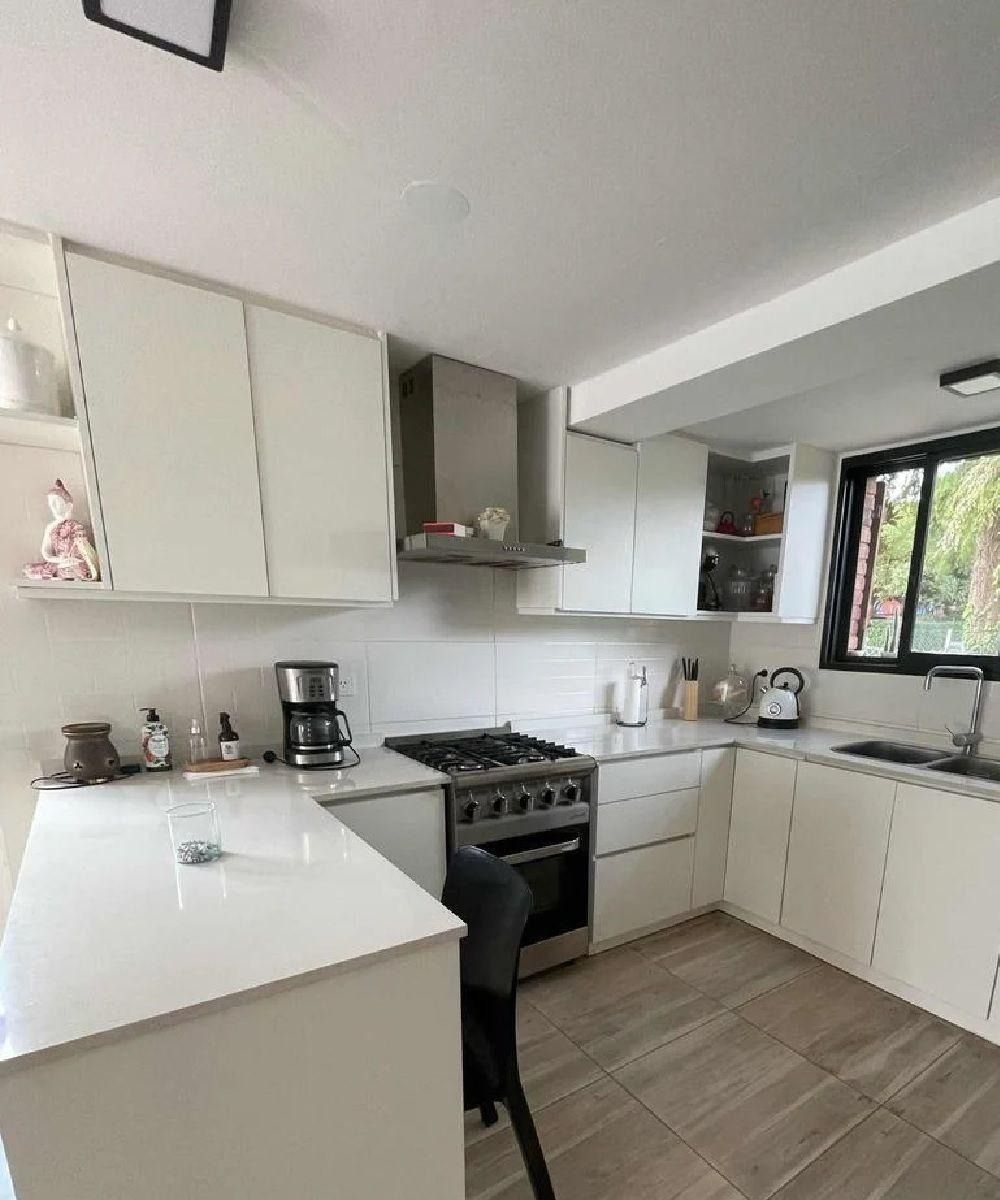 Cocina moderna blanca con armarios, encimeras y electrodomésticos.