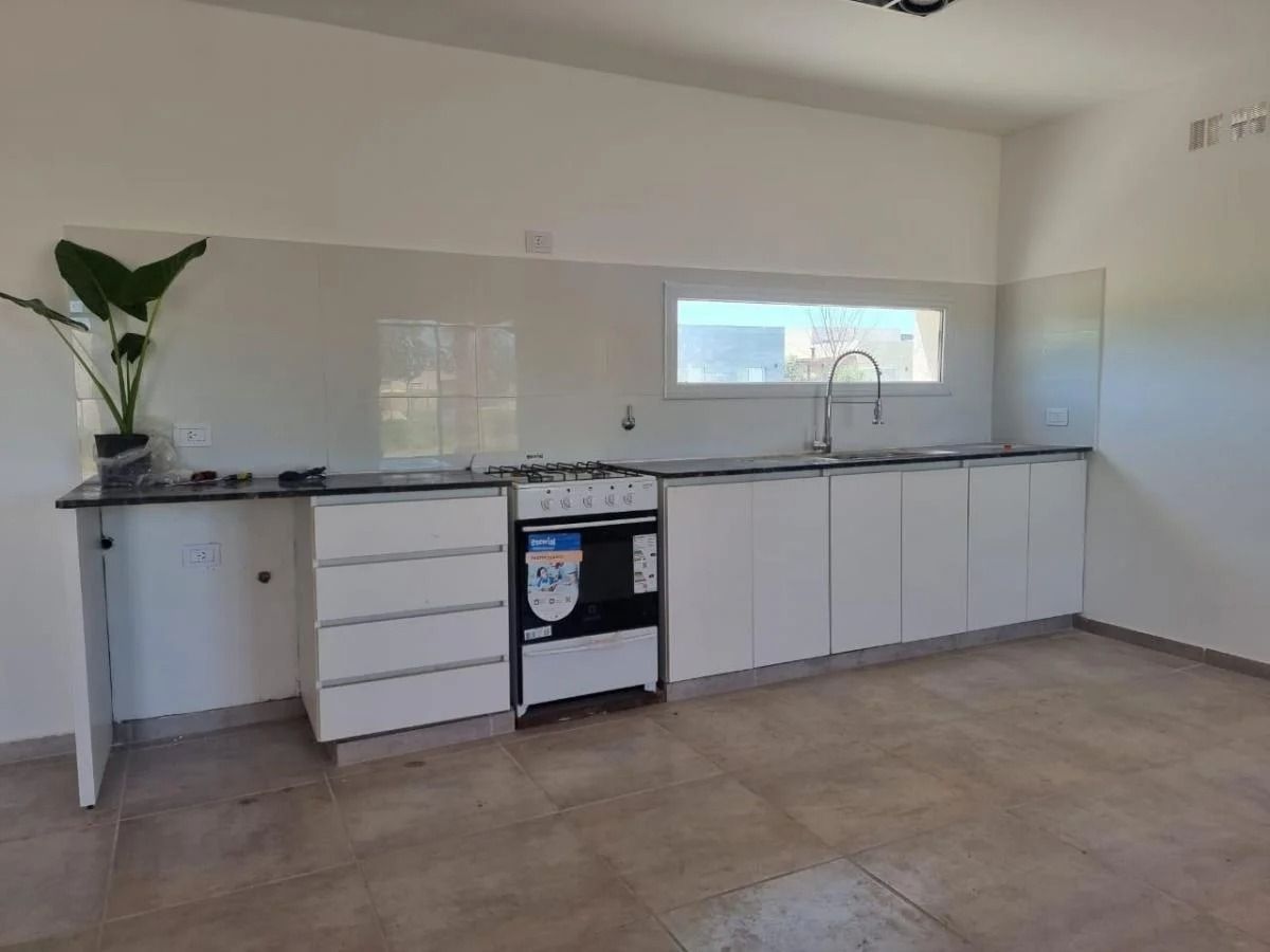 Moderna cocina blanca con armarios, estufa, fregadero y ventana.