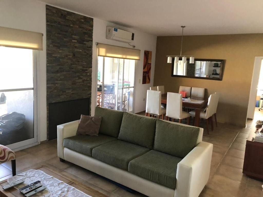 Sala de estar con sofá, mesa de comedor y pared decorativa de piedra.