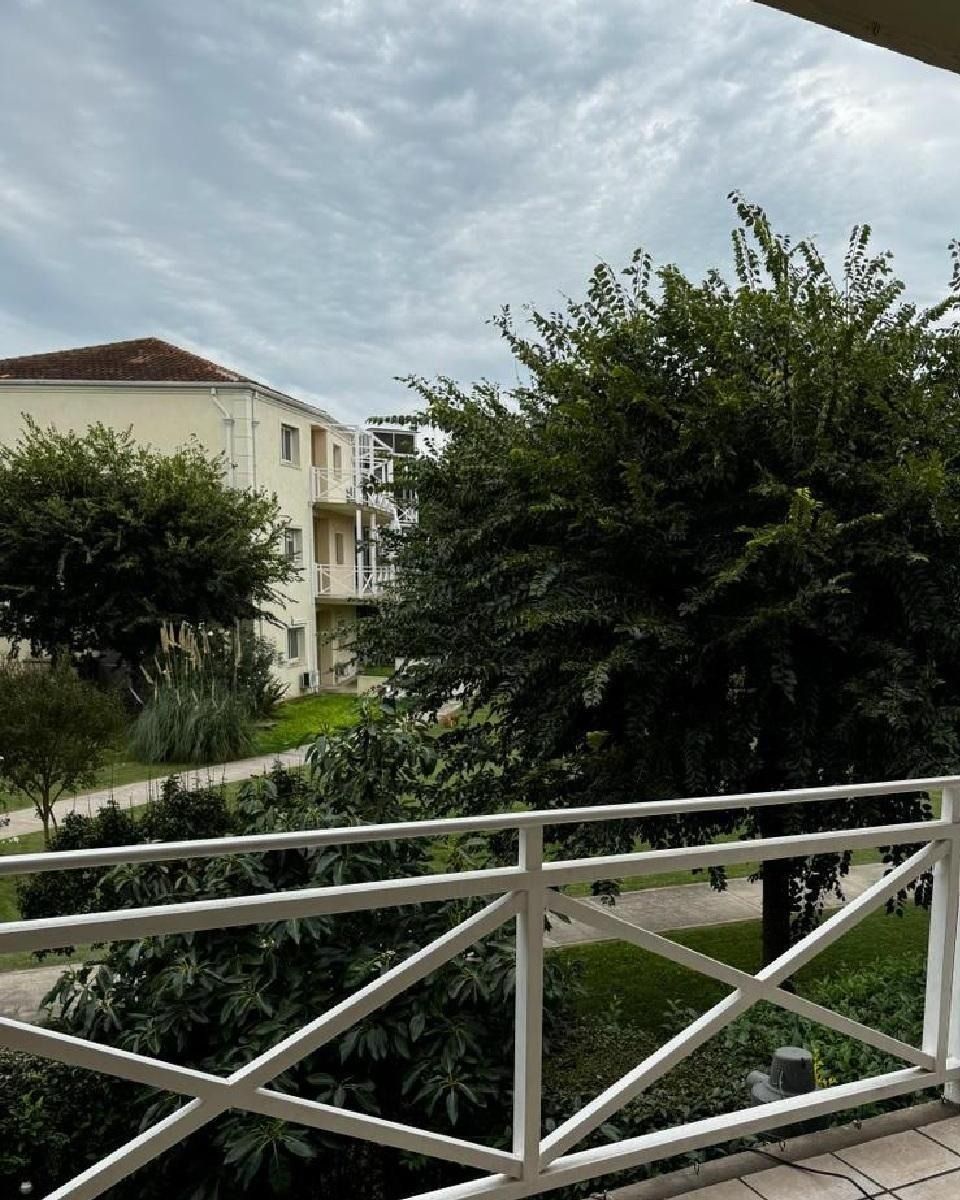 Barandilla blanca con vistas a árboles verdes, edificios y un cielo nublado.