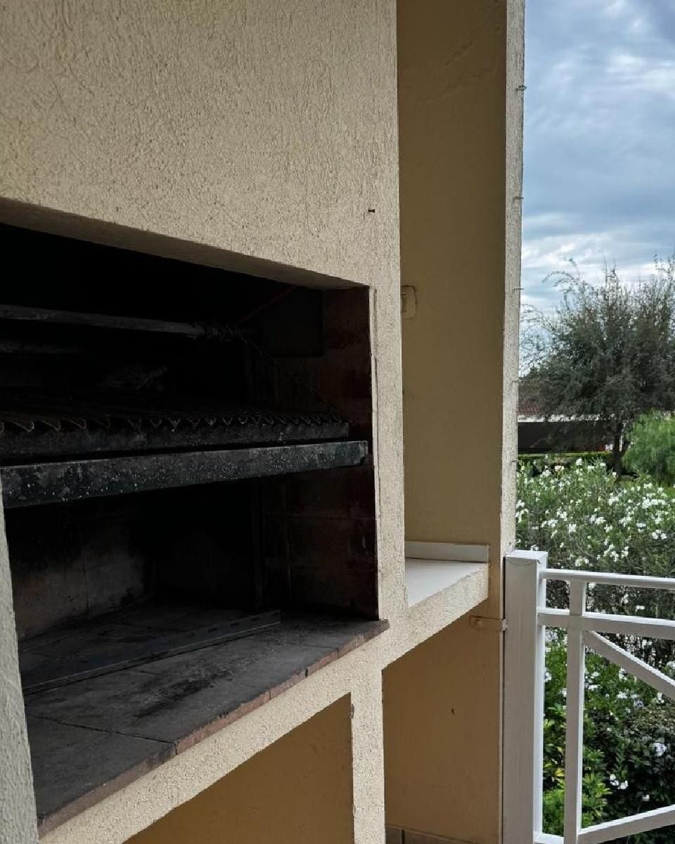 Barbacoa exterior empotrada en un balcón con barandilla blanca. Se ve el cielo.