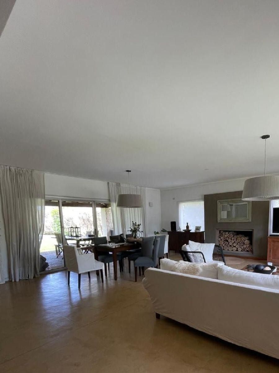 Espacio diáfano con comedor, zona de estar y chimenea; tonos neutros, luz natural.