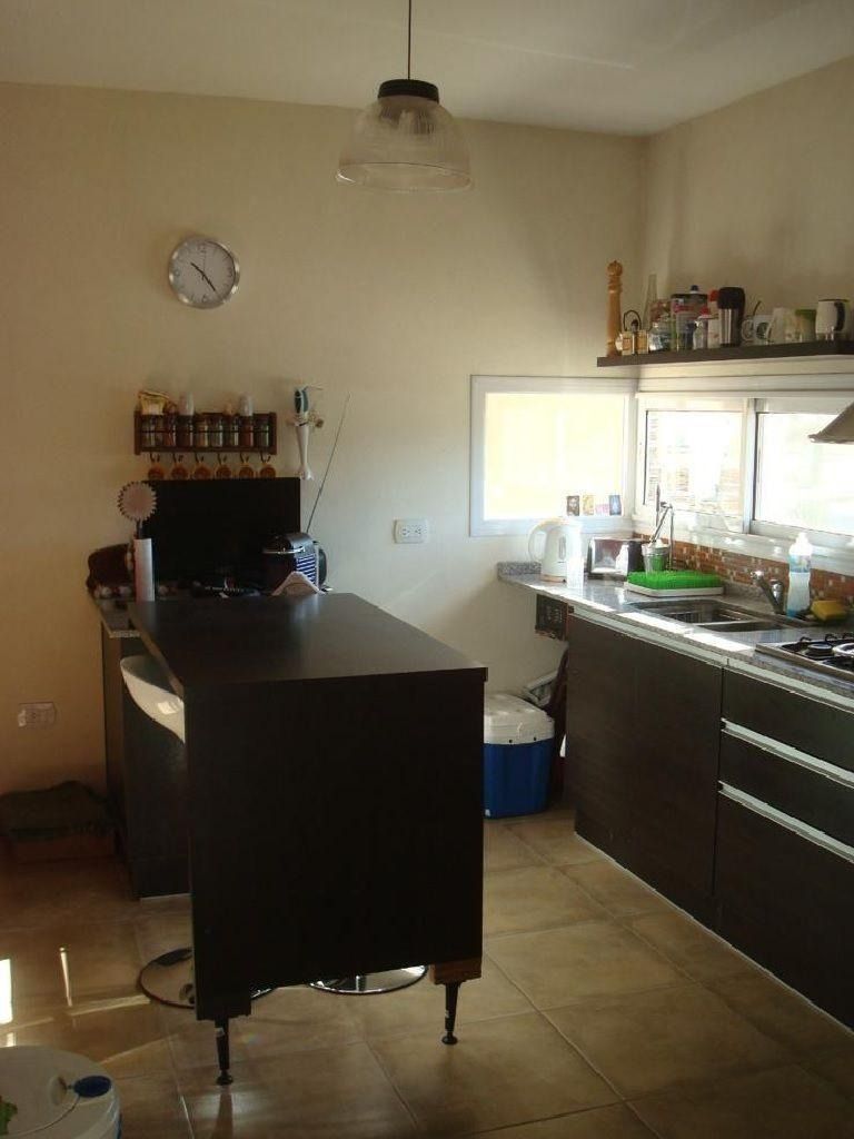 Cocina con armarios de color marrón oscuro, una isla central y un reloj en una pared color crema.