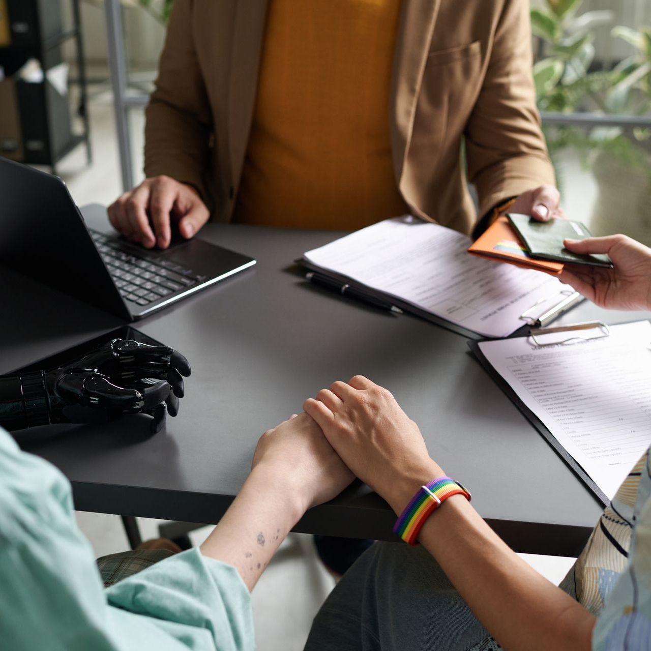 Un gruppo di persone è seduto a un tavolo con dei documenti e un computer portatile.