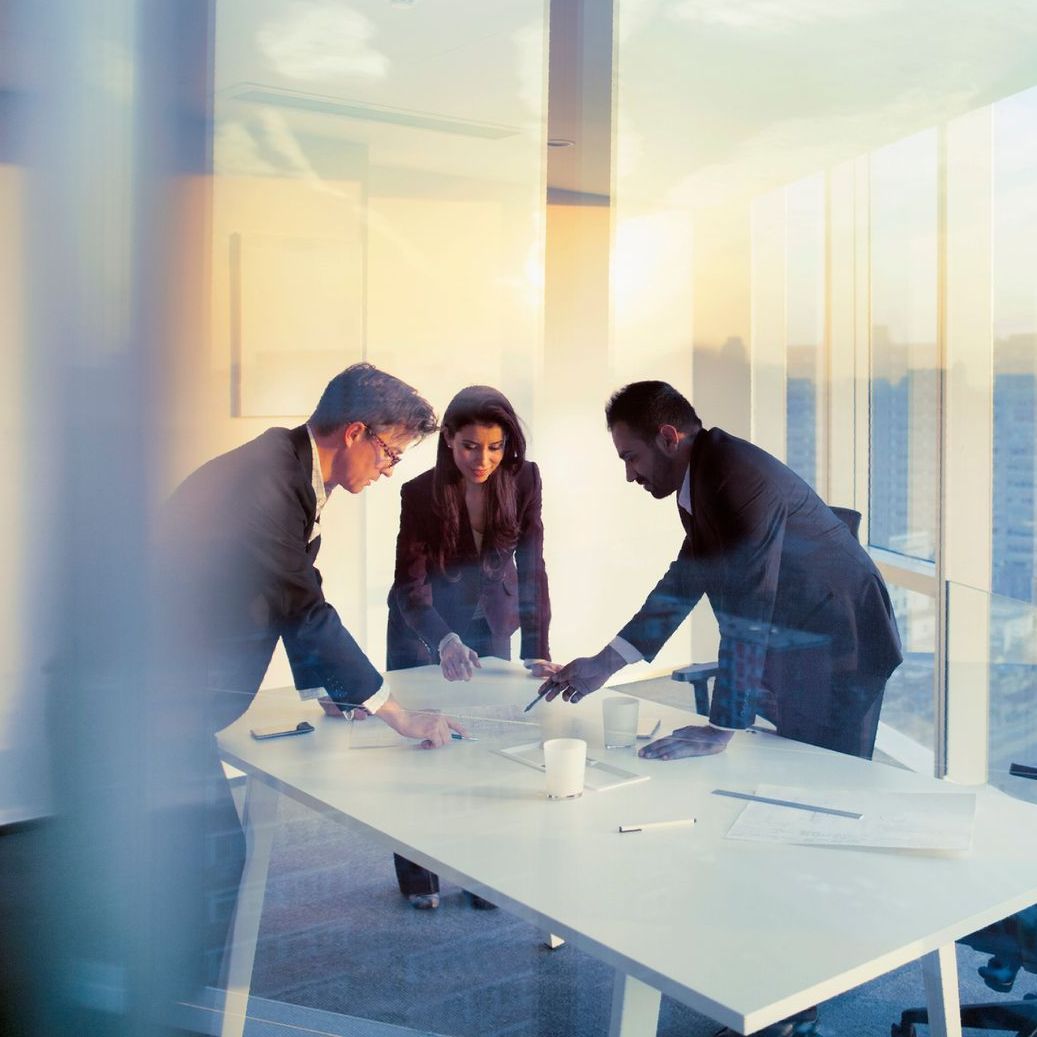 Un gruppo di persone è seduto attorno a un tavolo e guarda qualcosa