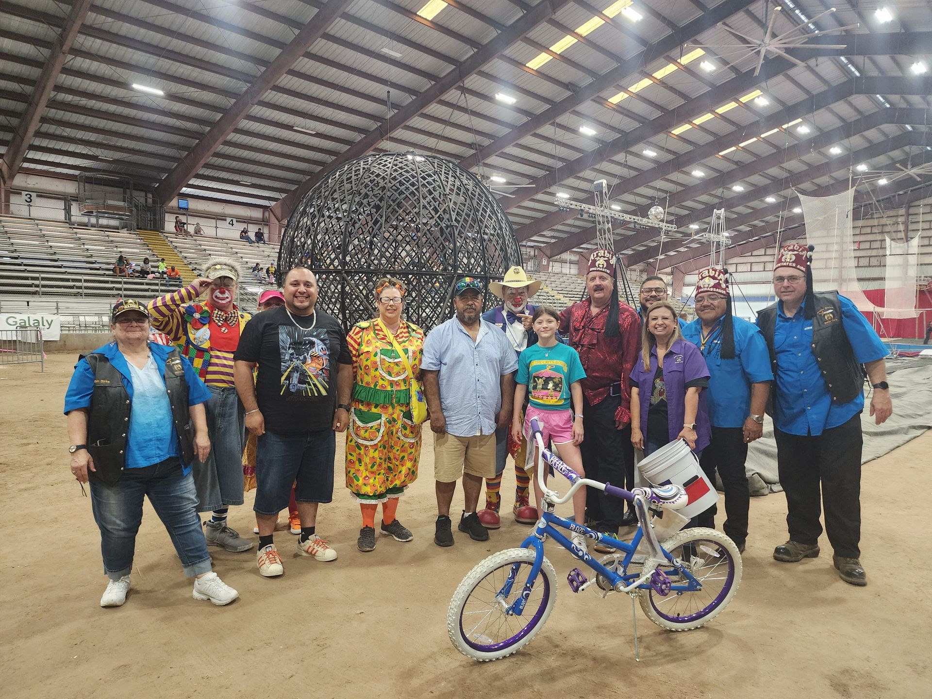 A group of people are posing for a picture with a bicycle. | Arabia Shrine Circus