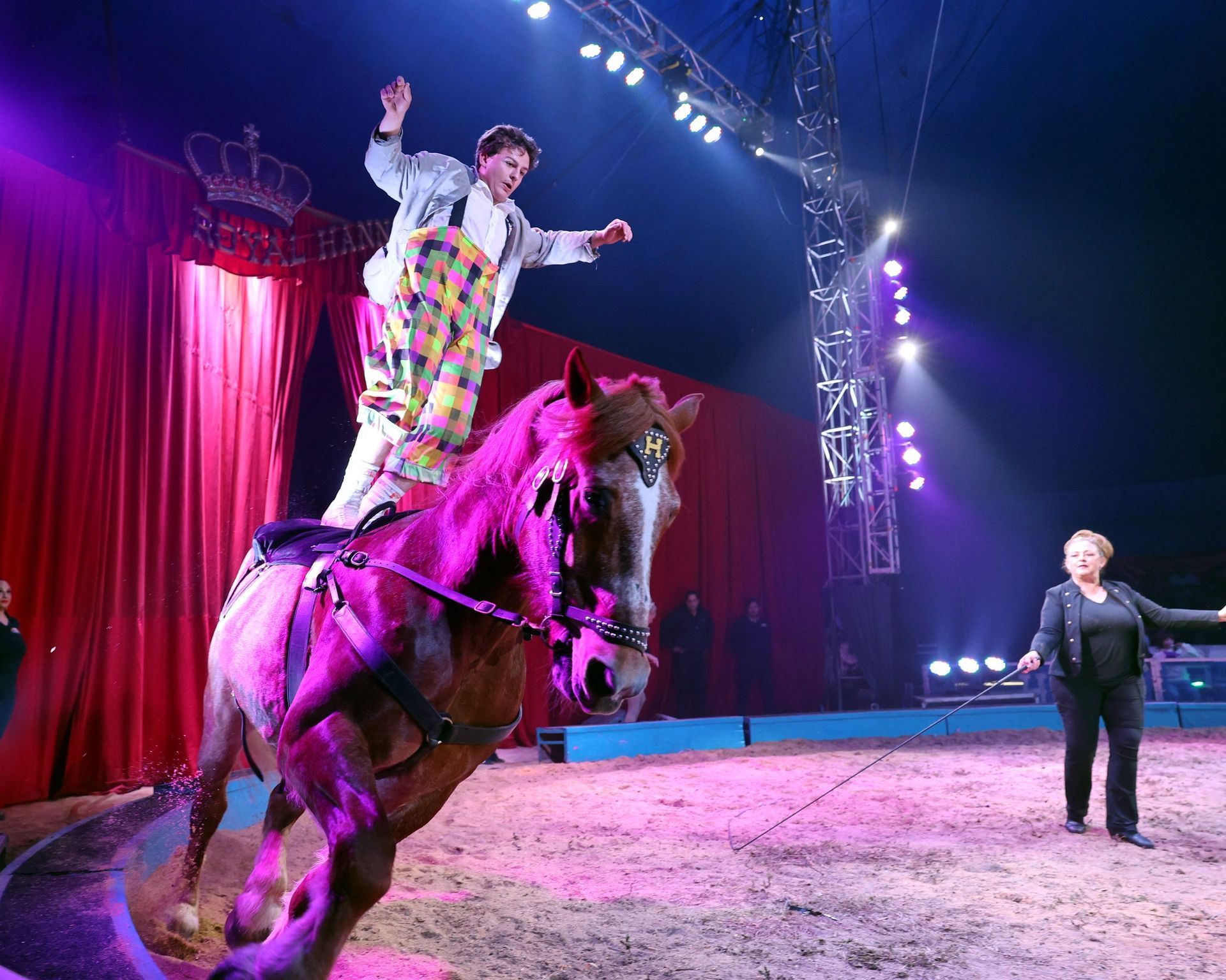 A clown is riding a horse in a circus arena | Arabia Shrine Circus