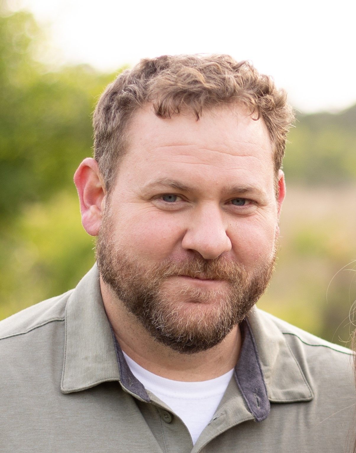 A man in a green shirt is smiling for the camera