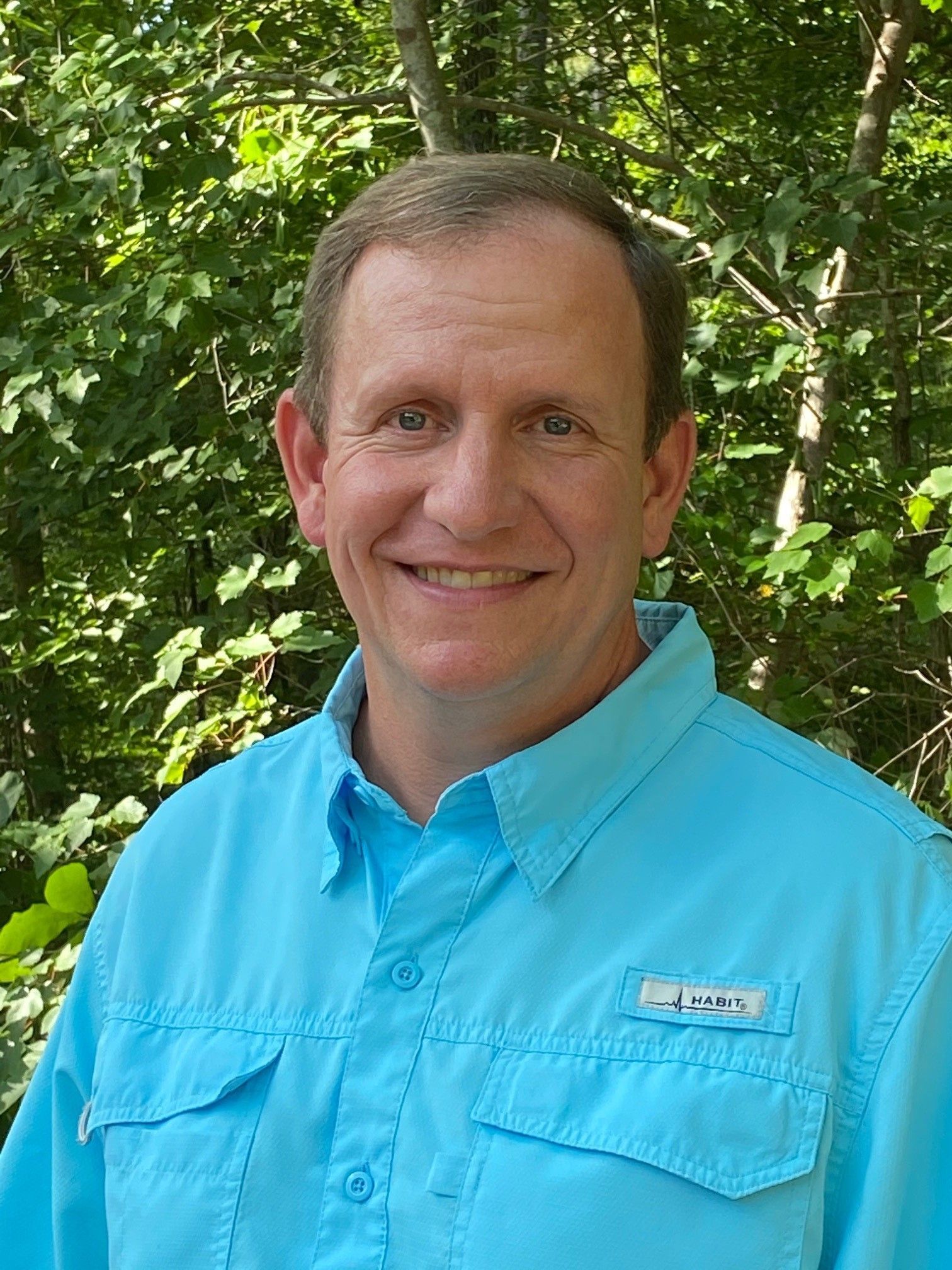 A man in a green shirt is smiling for the camera