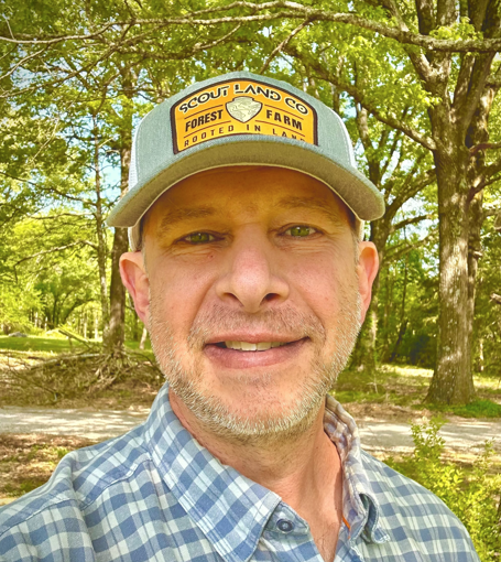 A man in a green shirt is smiling for the camera