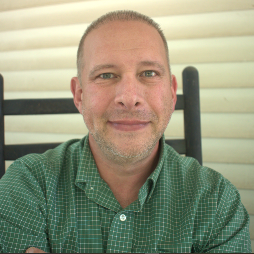 A man in a green shirt is smiling for the camera
