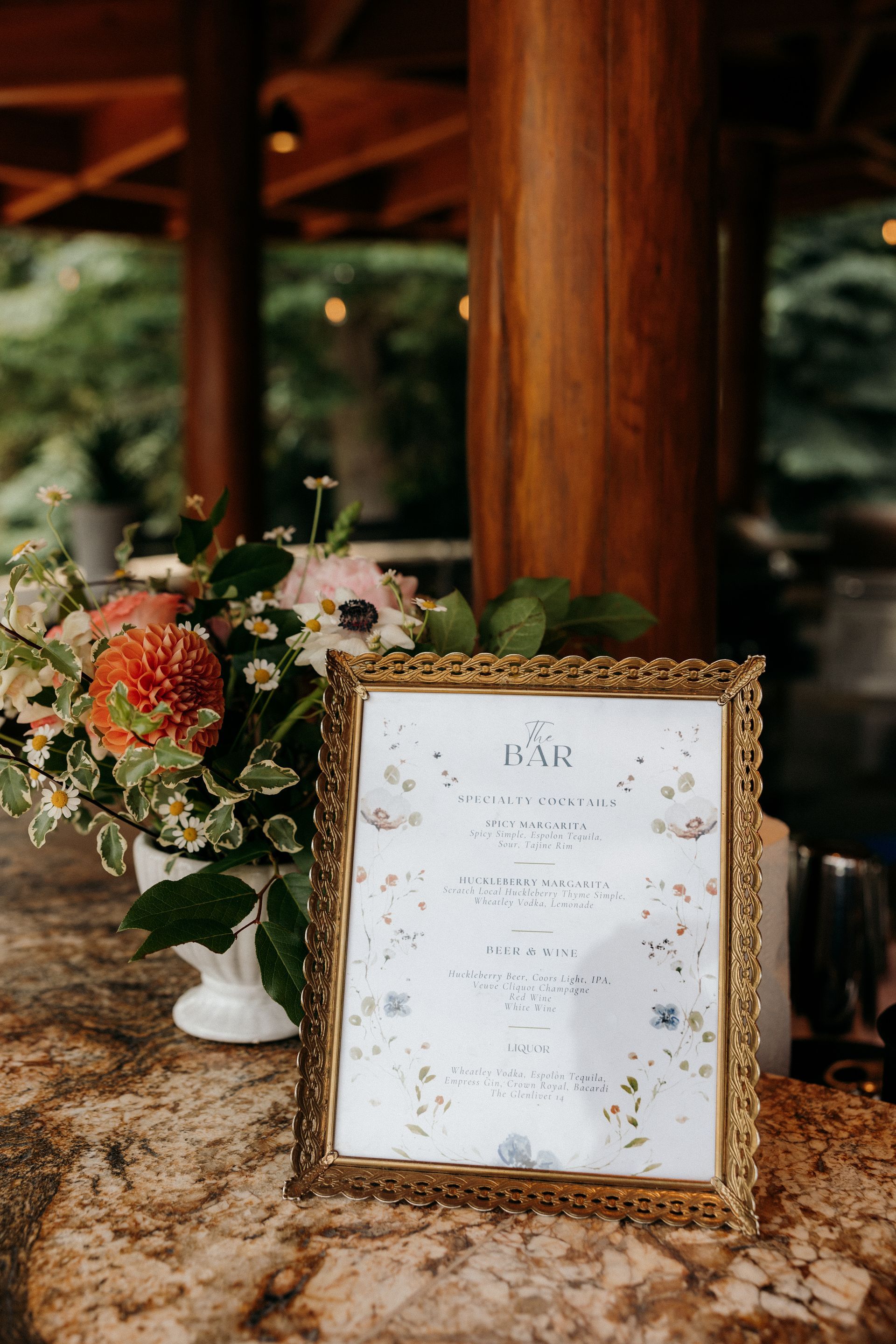 A framed sign is sitting on a table next to a vase of flowers.