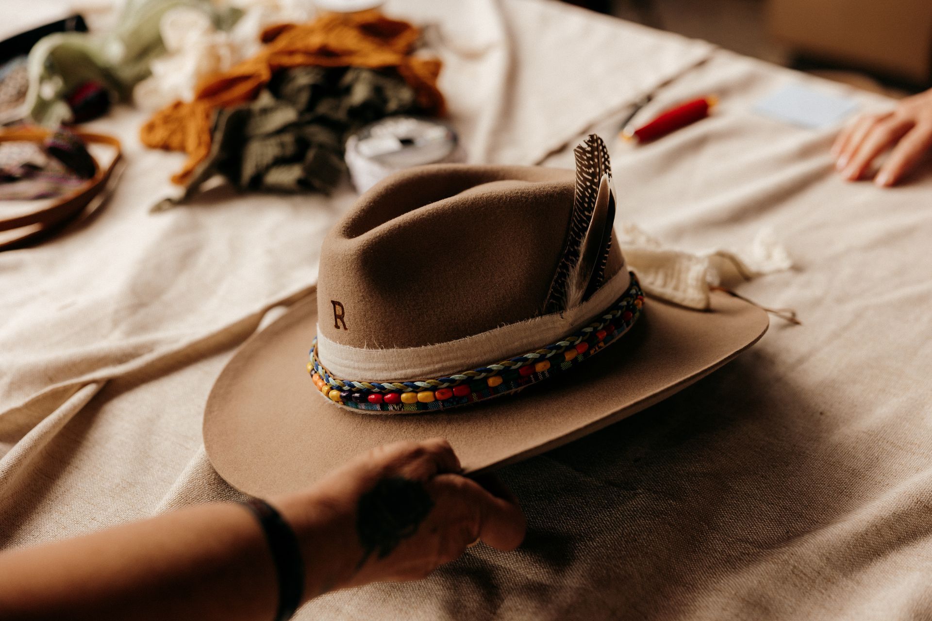 A person is holding a cowboy hat on a bed.