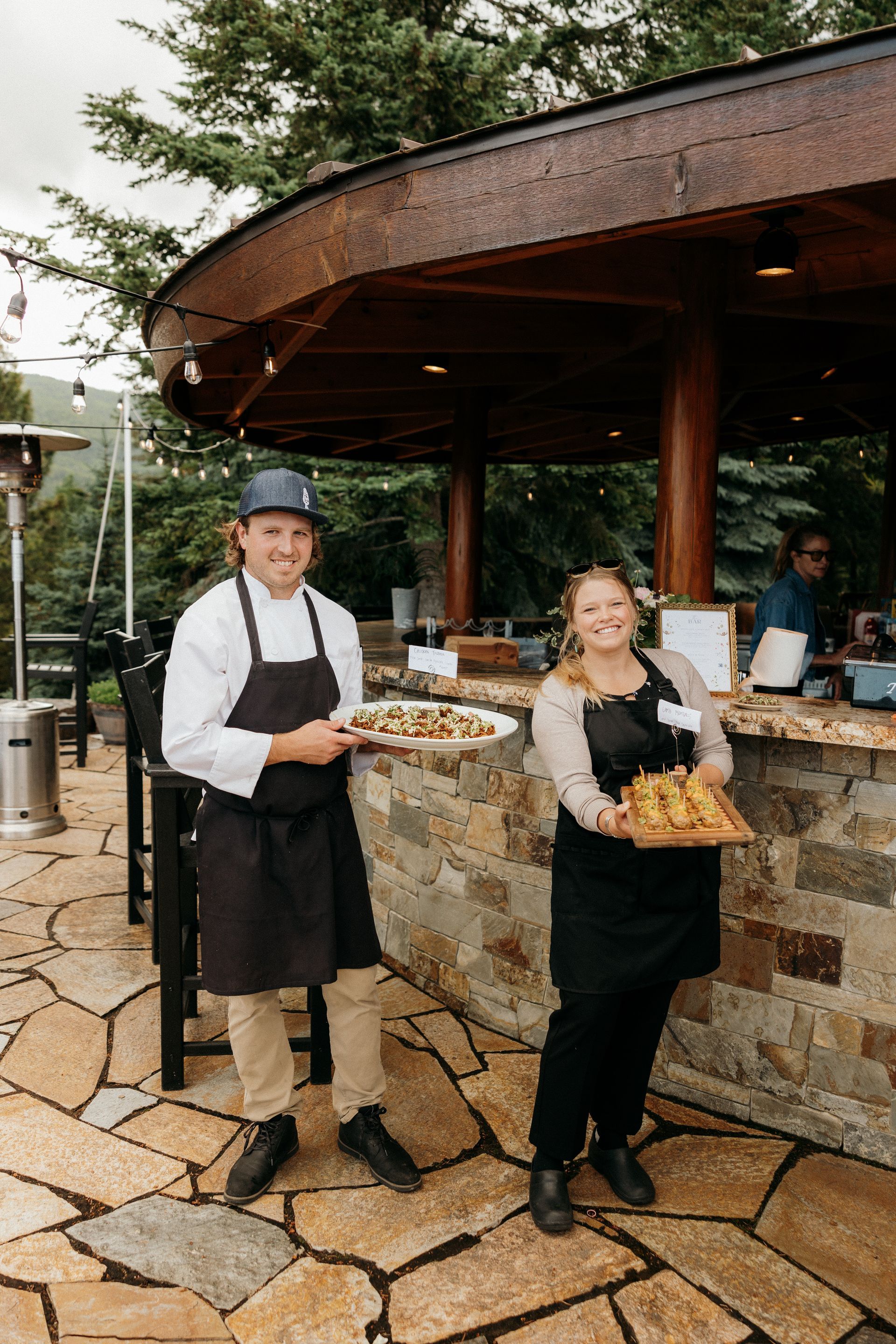 A man and a woman are standing next to each other holding plates of food.