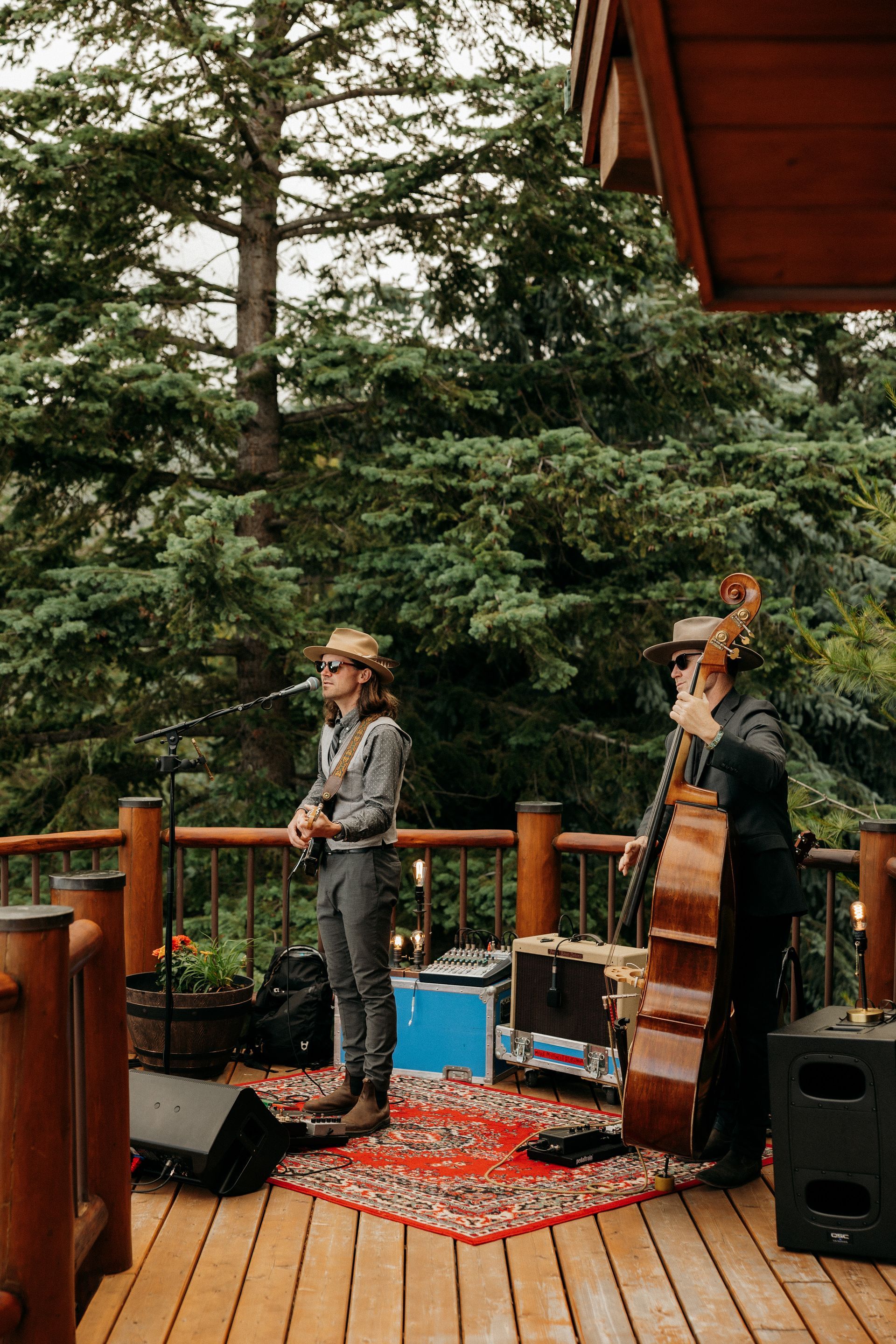 Two men are playing instruments on a wooden deck.