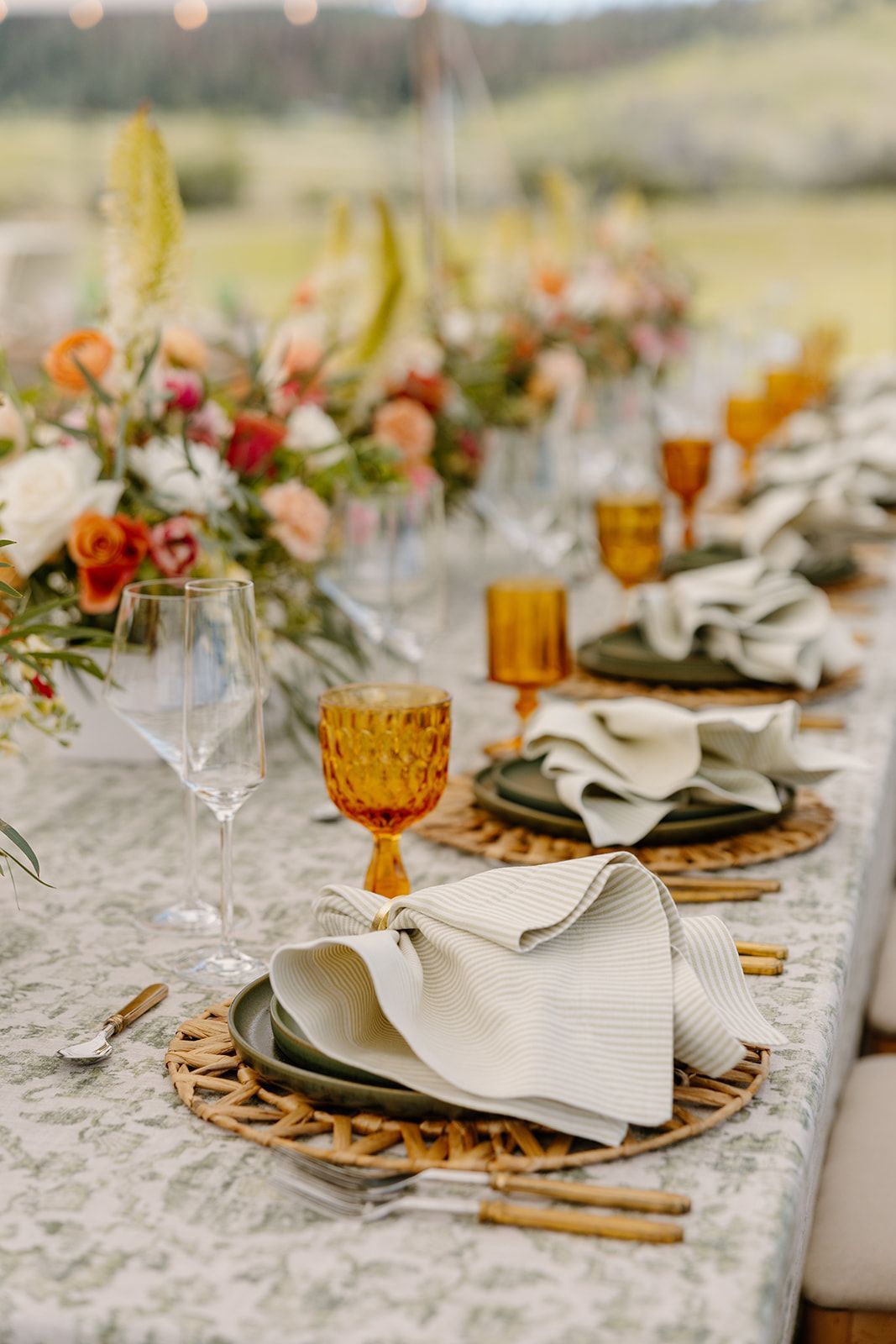 A long table with plates , glasses , and napkins on it.
