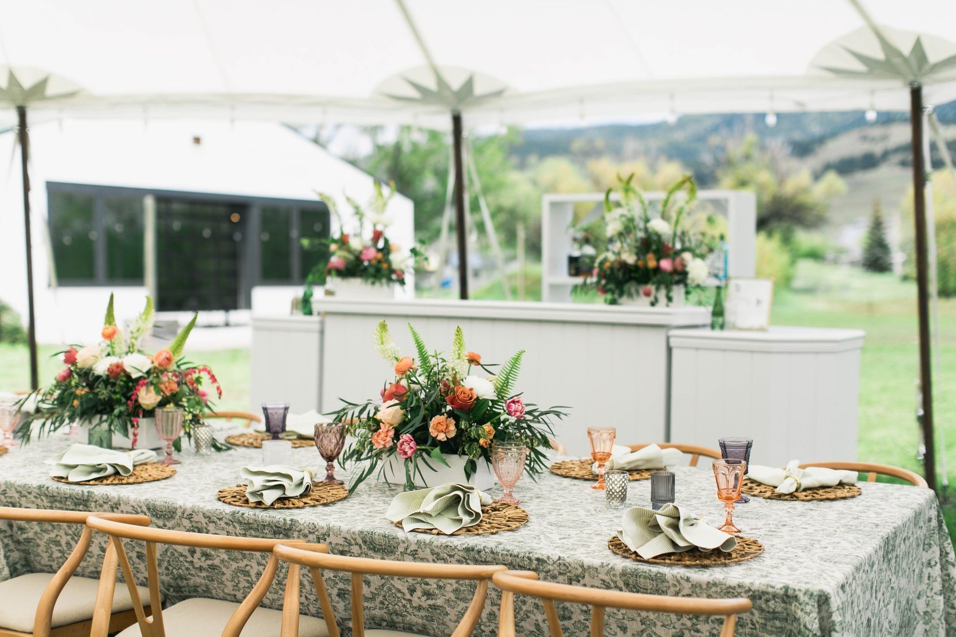A long table with flowers on it under a tent.