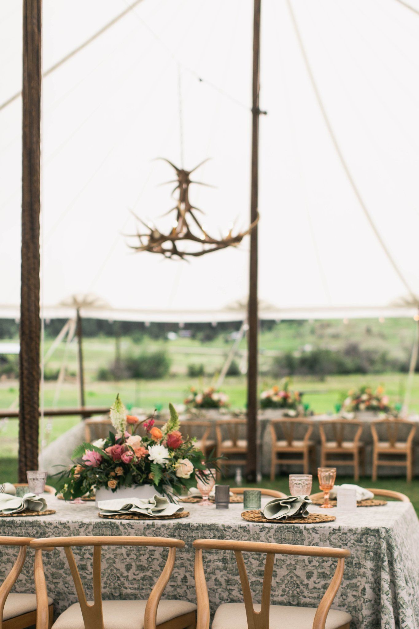 A table and chairs under a tent with a chandelier hanging from the ceiling.