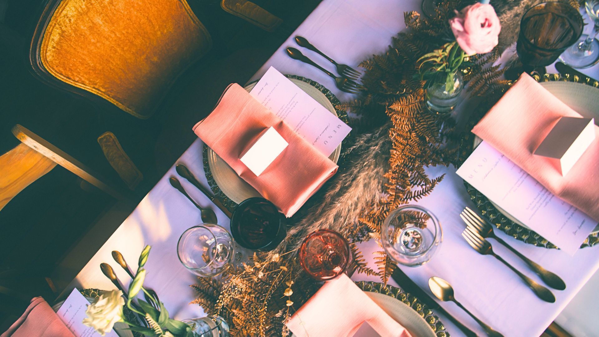 A table with plates , napkins , utensils , and flowers on it.