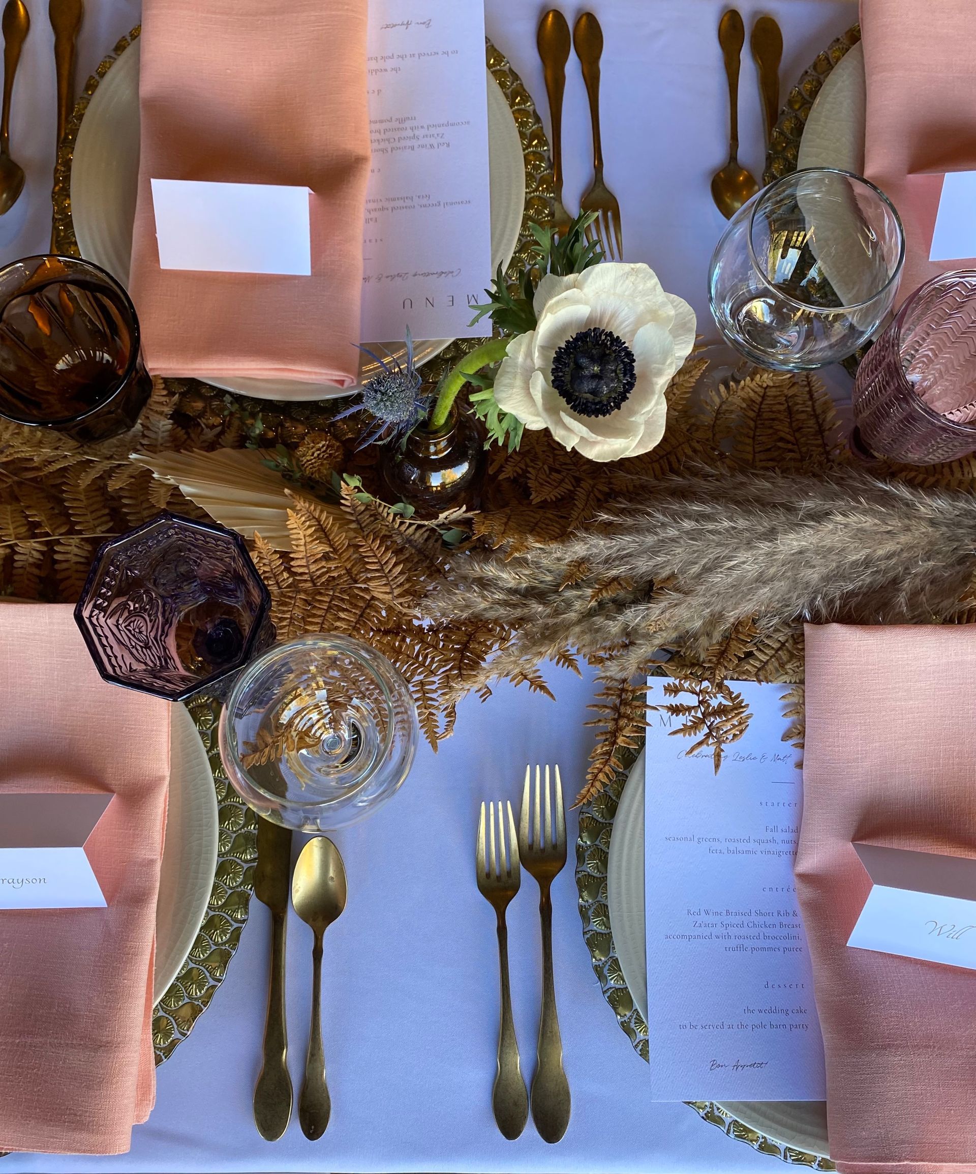 A table with pink napkins and silverware and flowers on it
