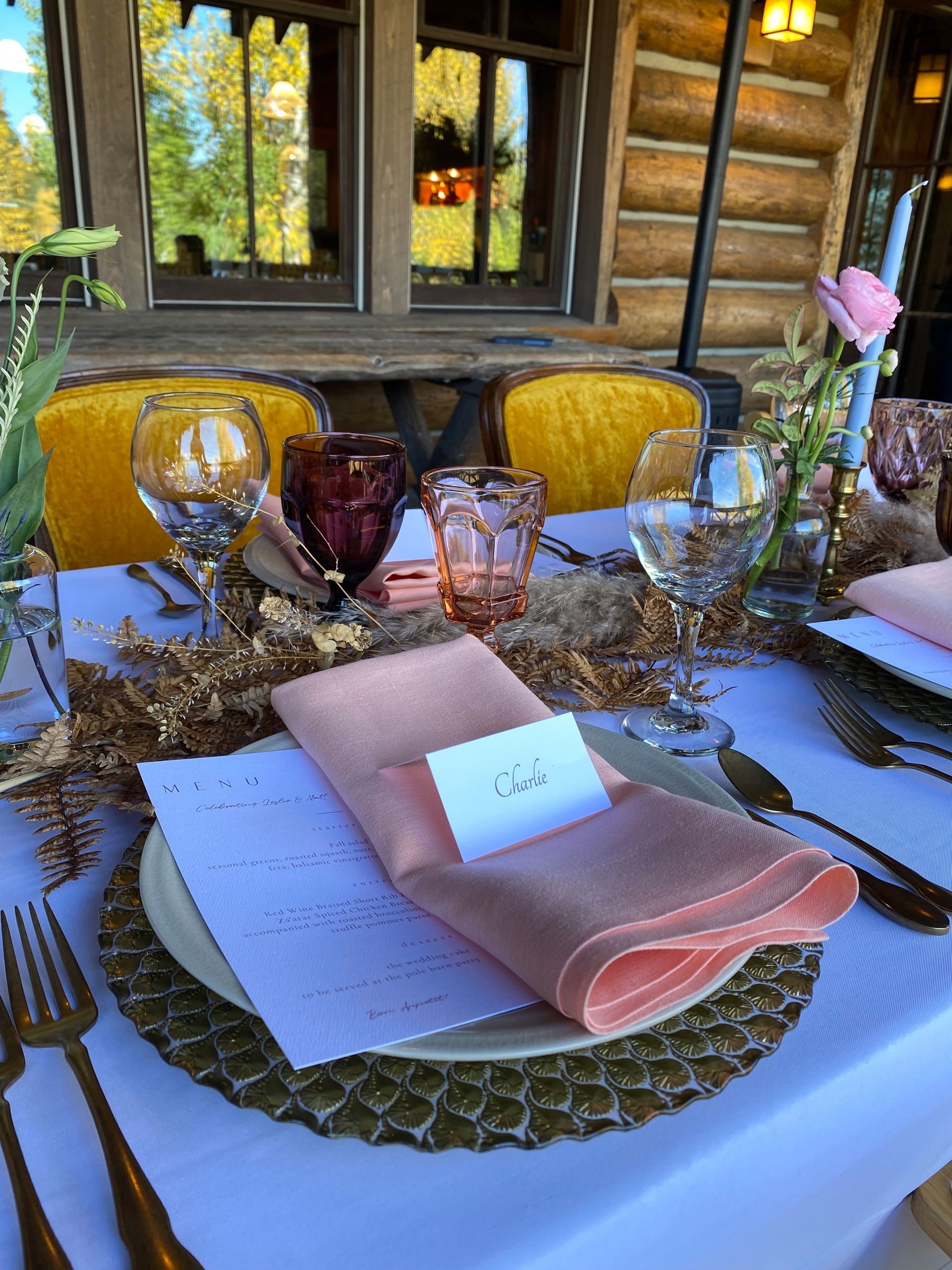 A table set for a wedding reception with plates , napkins , glasses , and silverware.