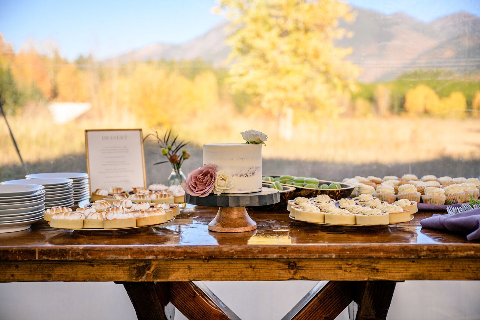 A wooden table topped with plates of food and a cake.
