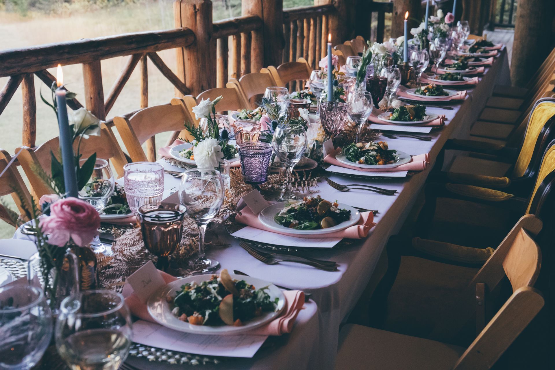 A long table with plates of food and glasses on it.