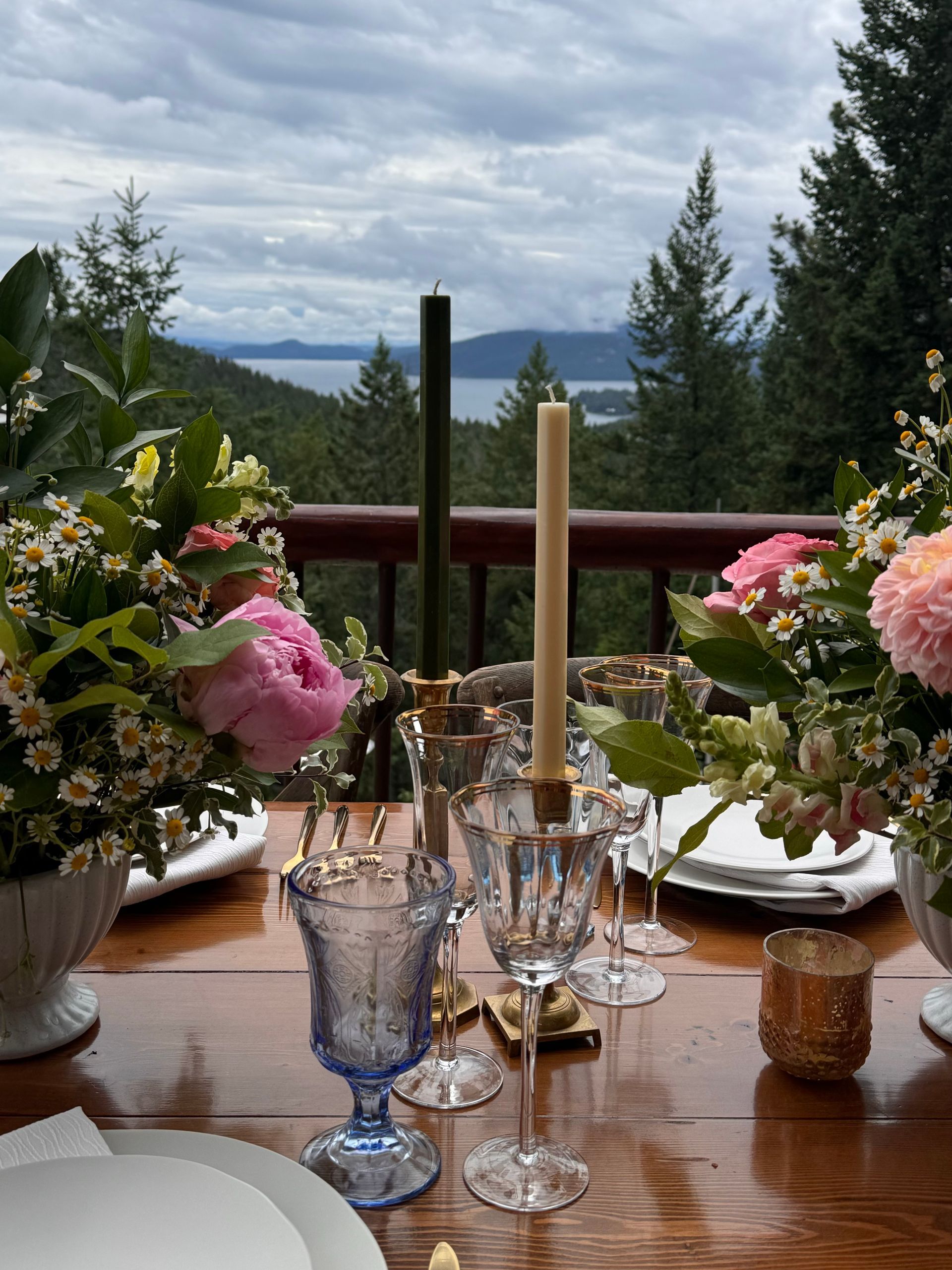 A wooden table with plates , glasses , candles and flowers on it