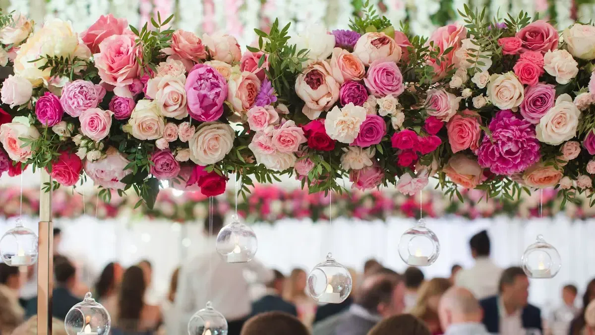 A group of people are sitting at a table with flowers hanging from the ceiling.