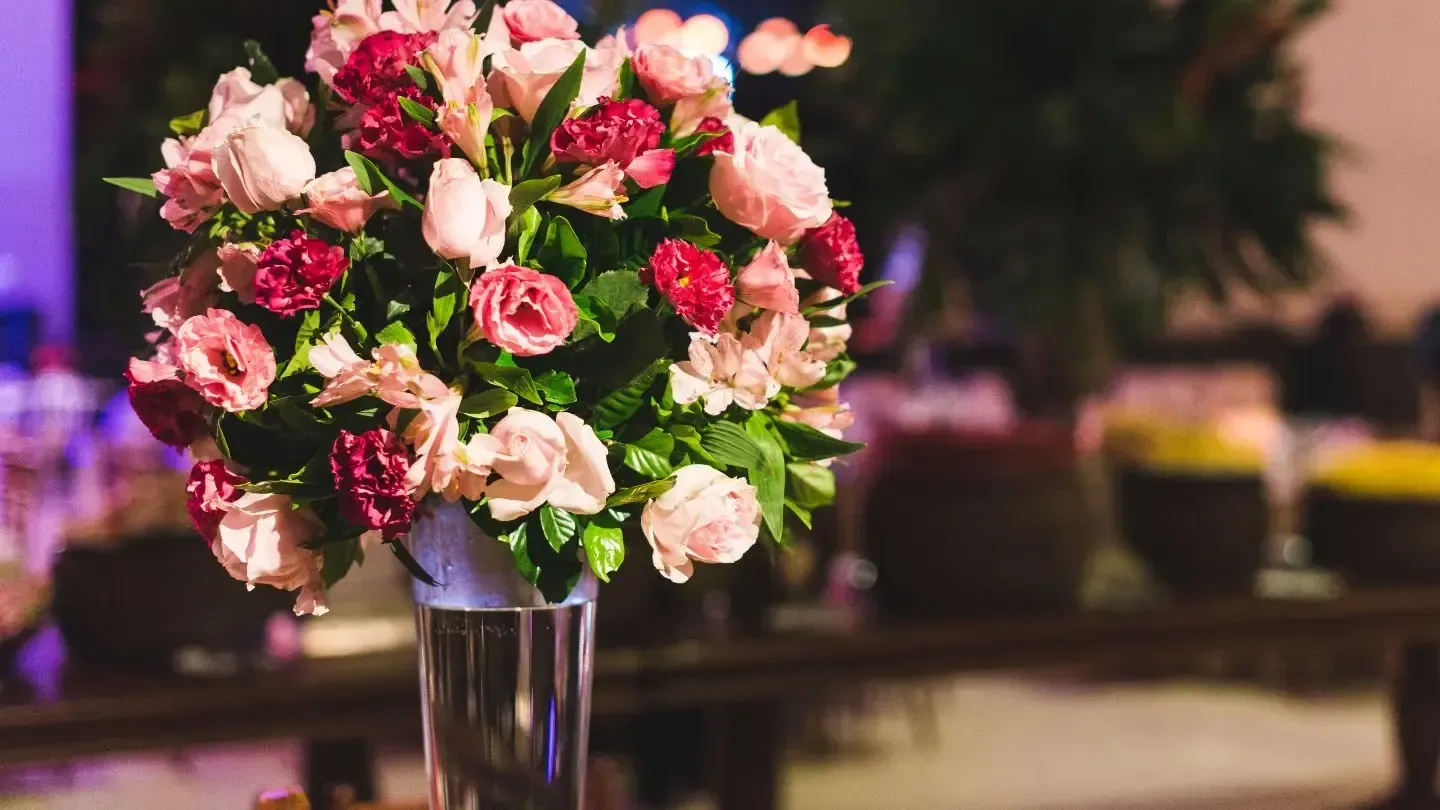 A vase filled with pink and red flowers is sitting on a table.