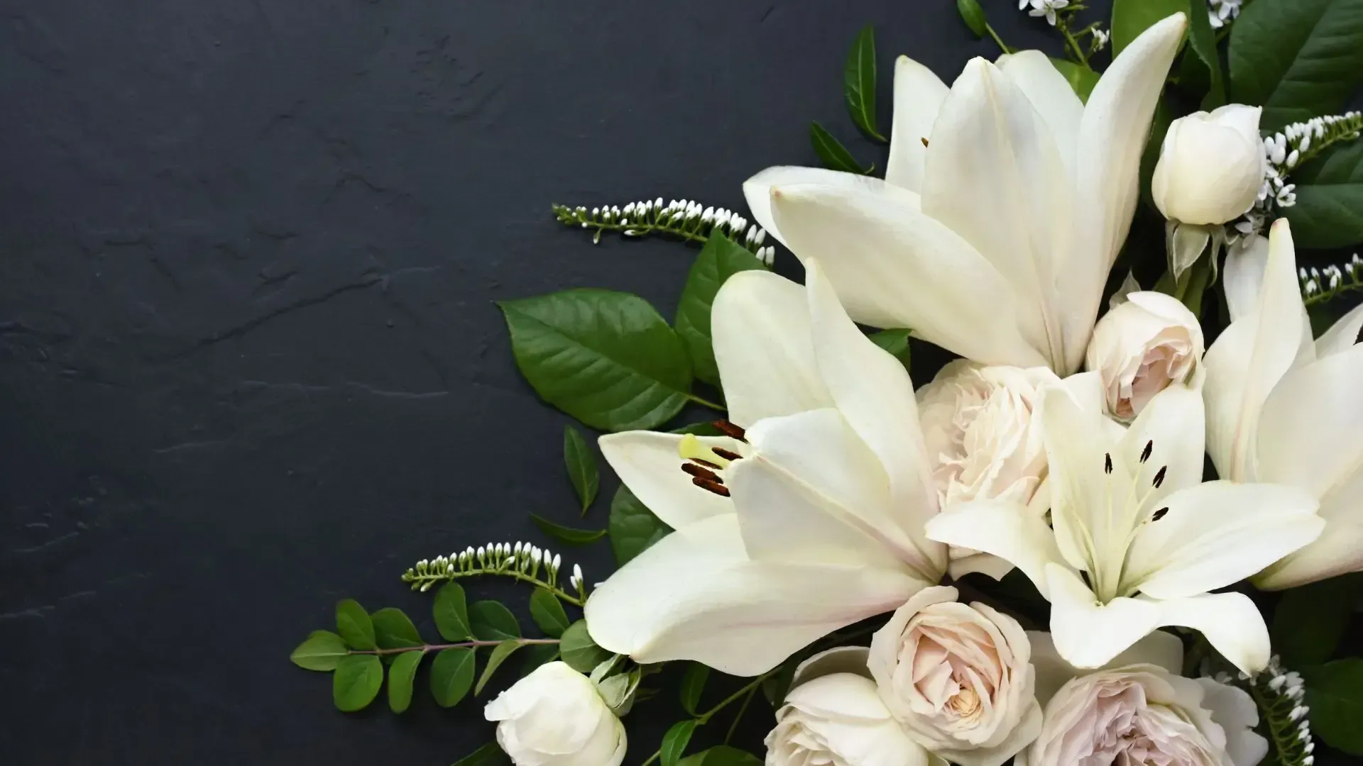 White lilies and roses on a dark background.