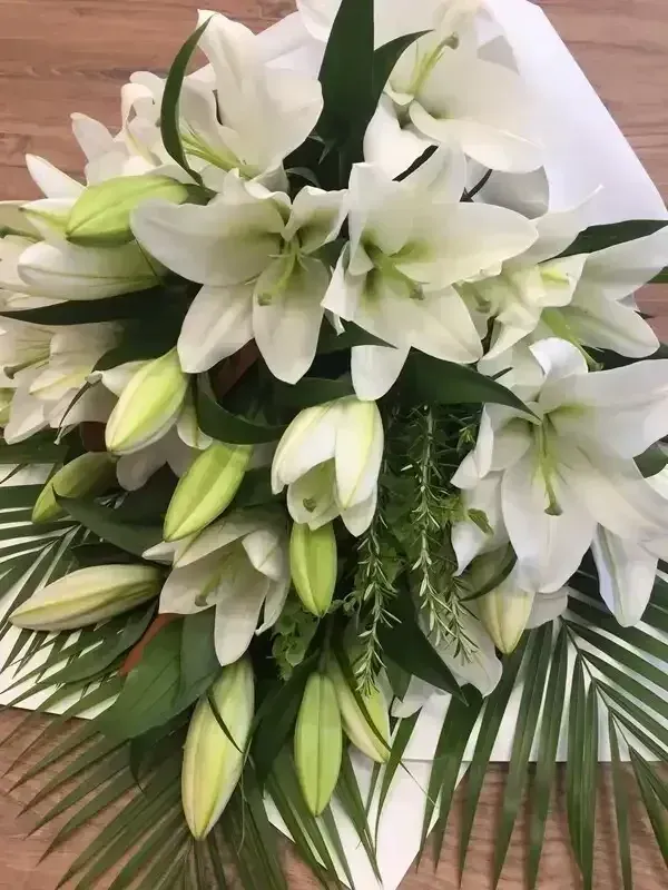 White lilies and green foliage in a floral bouquet.