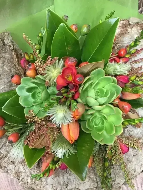 Floral arrangement with green succulents, orange berries and red flowers.